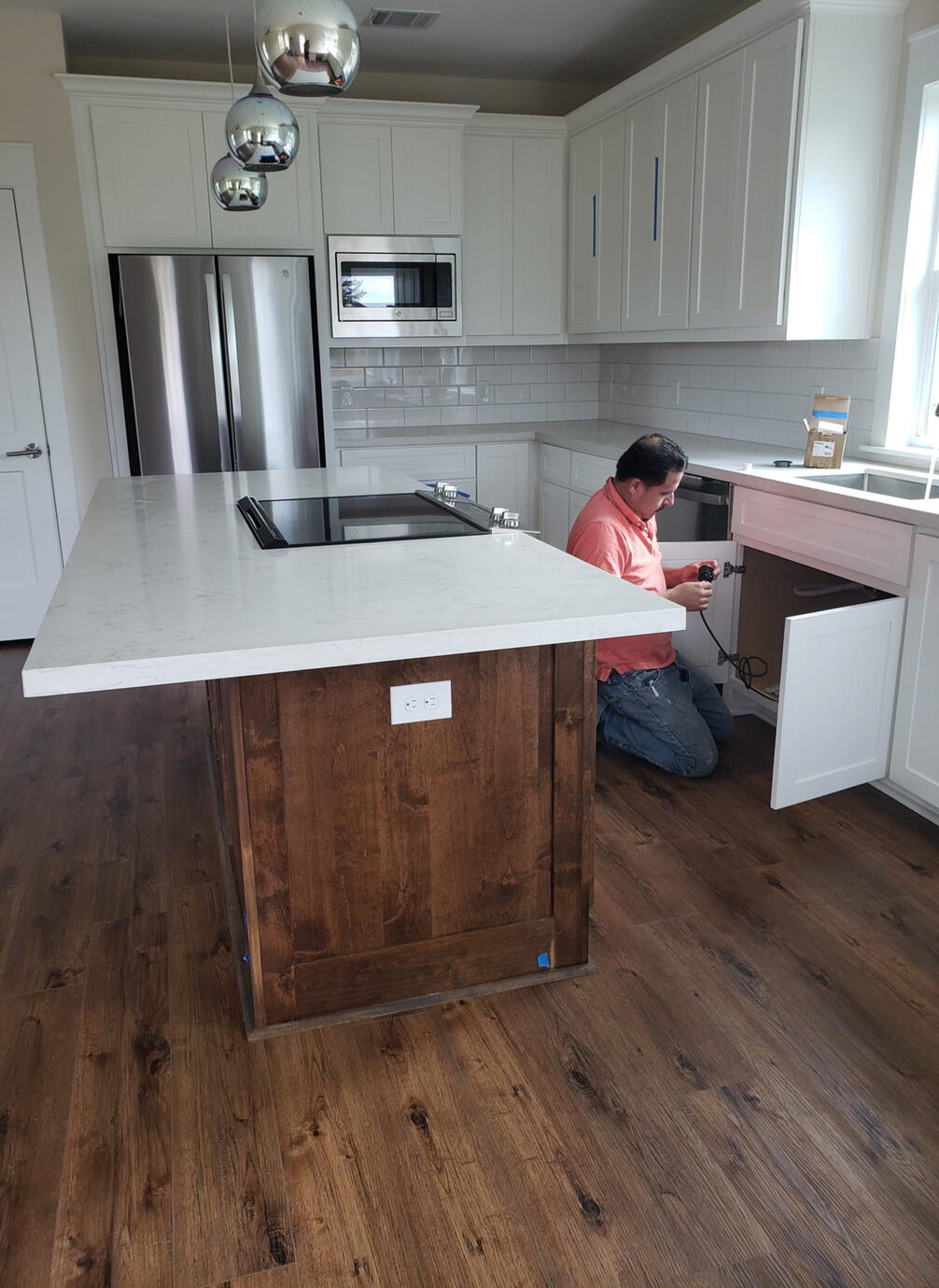 B Master Juan working inside of a beautiful sunlit kitchen with maple wood and pure white granite and cabinetry.